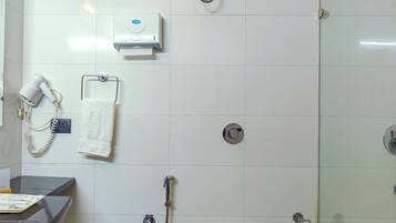 A bathroom with a toilet, shower, and a hairdryer on the wall.