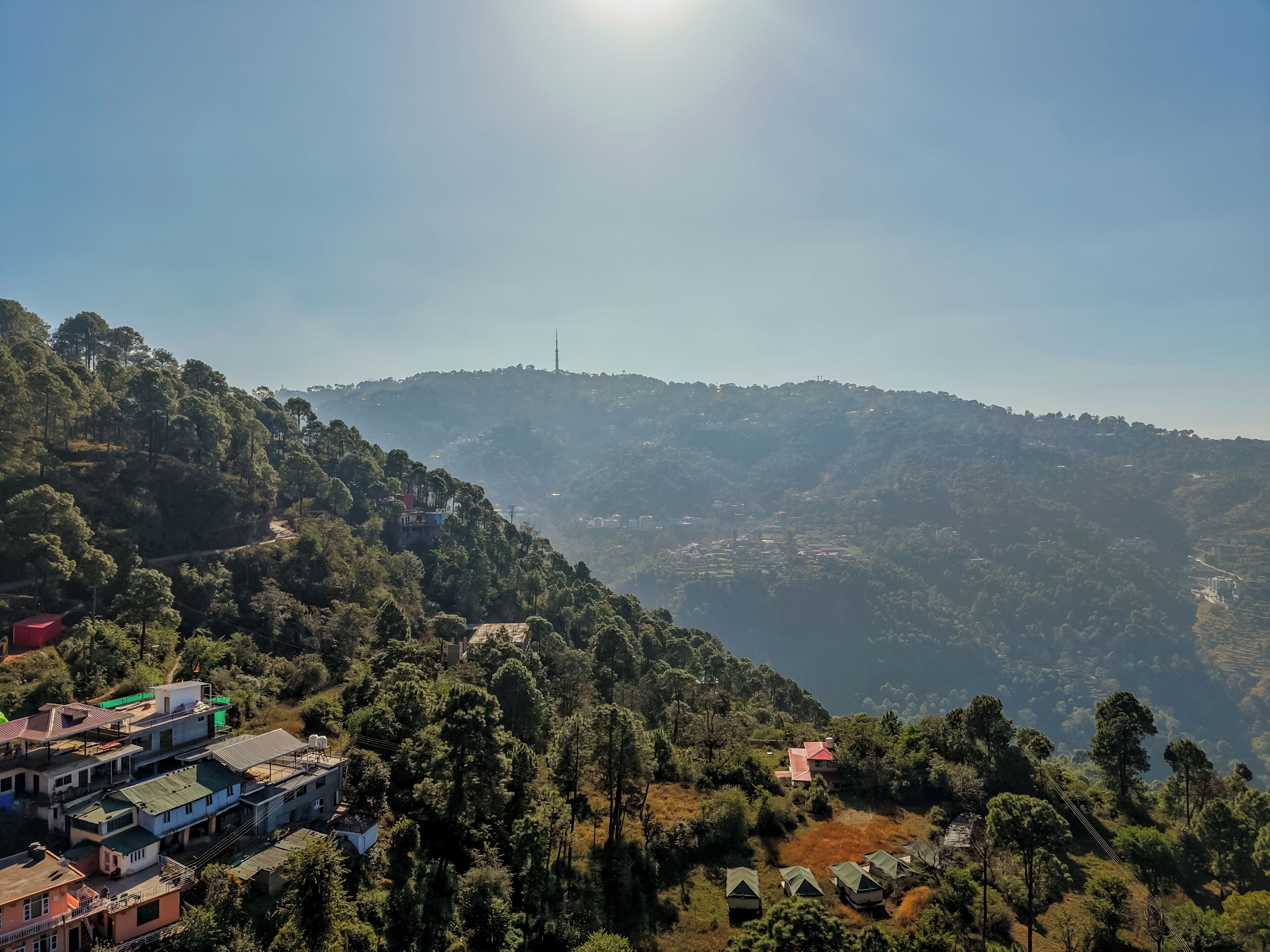 A mountainous landscape with a clear sky, a prominent tower, and scattered buildings.
