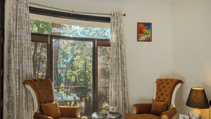 A room with two brown upholstered chairs, a small round table, a lamp, and a painting on the wall. - Alaya Stays 3BHK Golden Meadow Villa (Kasauli)