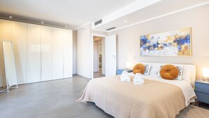 Ett modernt hotellrum med en stor säng, en tavla på väggen och en rymlig klädkammare.