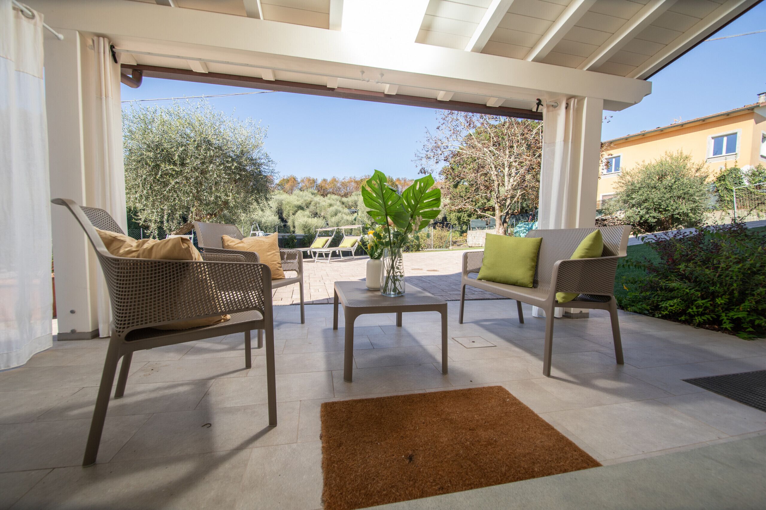 Une terrasse extérieure avec des meubles en osier, une petite table et une plante en pot.