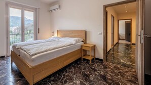 Ein Schlafzimmer mit einem hölzernen Bett, einem Nachttisch, einem kleinen Tisch und einem großen Spiegel.