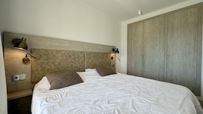 Ein Schlafzimmer mit einem großen Bett, zwei Wandleuchten, einem Holzschrank und einem Schalter am Wand.