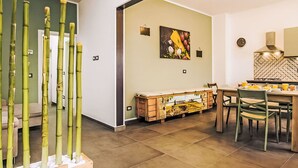 Una cocina moderna con comedor, que incluye una planta de bambú, un cuadro y un mueble de madera.