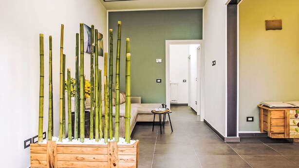 Un pasillo con un arreglo de plantas de bambú, un sofá, una mesita y un armario de madera.