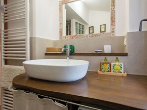 Une salle de bain avec un lavabo blanc, un miroir et un plan de travail en bois.