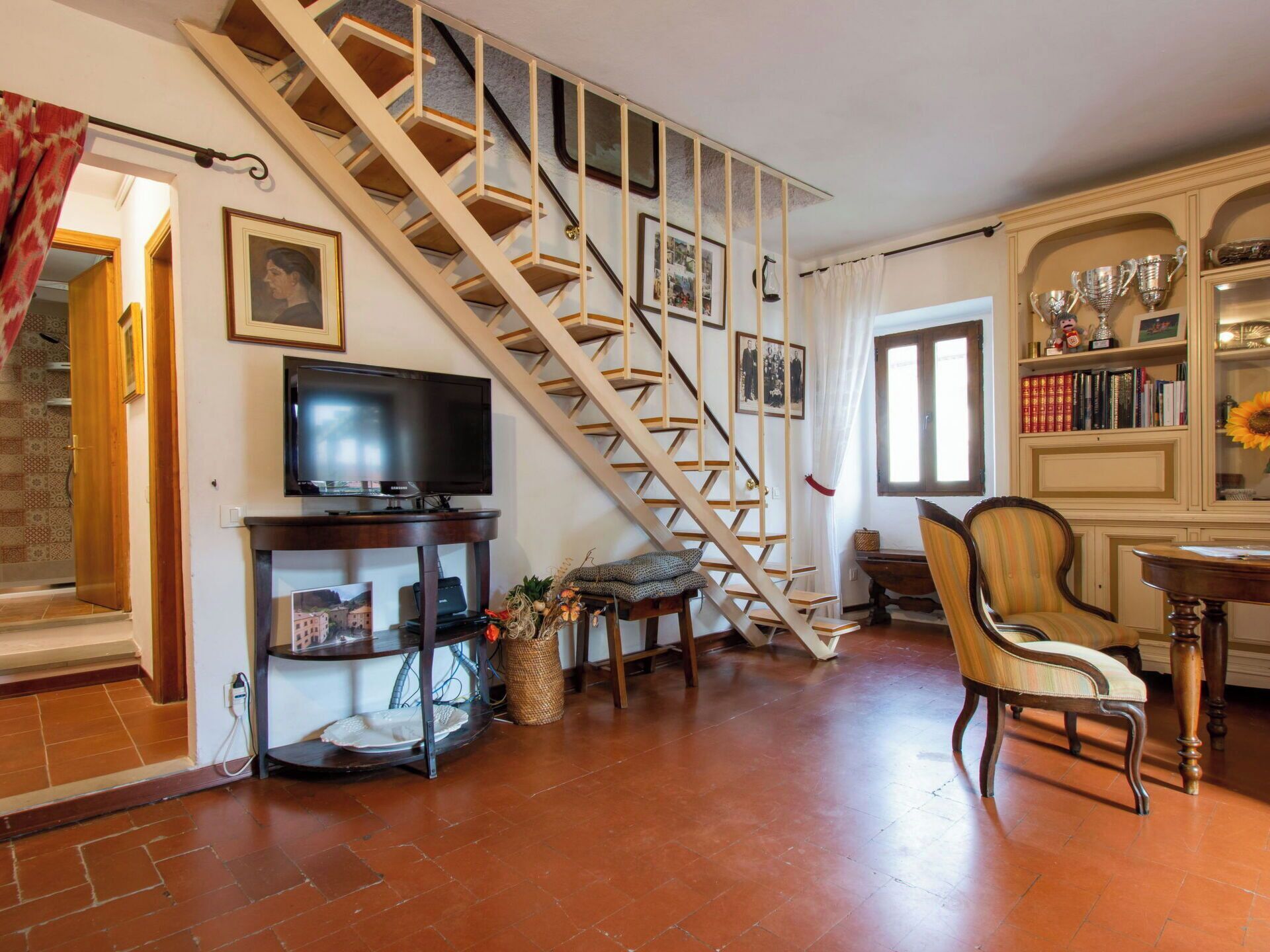 Ein Wohnzimmer mit Holzboden, einer Holztreppe, einem Fernseher, einem Kamin und einem Bücherregal.