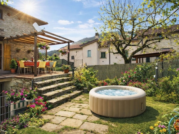 Ein Steinhaus mit Terrasse, Sitzgelegenheiten im Freien und einem Whirlpool.