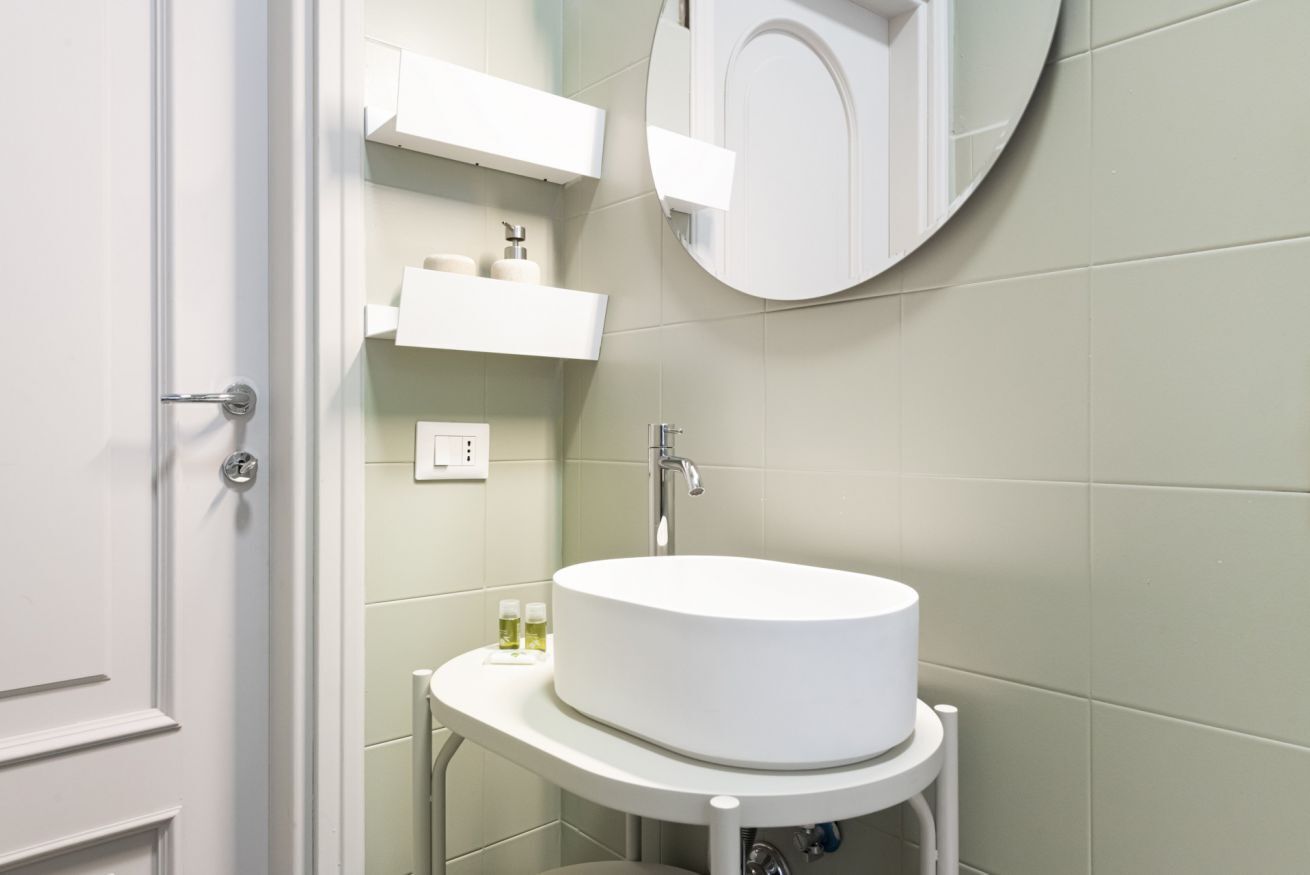 Ein Badezimmer mit einem weißen Waschbecken, einem Spiegel und einer Tür.
