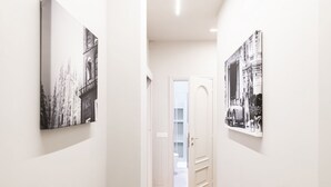 Un pasillo con paredes blancas, suelo de madera y dos fotografías blanco y negro en las paredes.