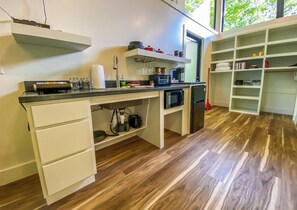 Een moderne keuken met witte kasten, een zwart aanrecht en een ingebouwde magnetron.