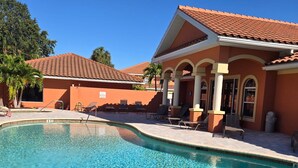 A swimming pool with a tiled deck, a building with a tiled roof, and a palm tree. - Cozy 2-bedroom condo in nice Fort Myers (Fort Myers)