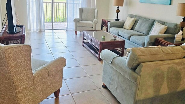 A living room with a sofa, armchair, and a ceiling fan. - Cozy 2-bedroom condo in nice Fort Myers (Fort Myers)