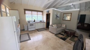 Un espacio habitable compacto con kitchenette, un sofá, una mesa de comedor y un ventilador de techo.