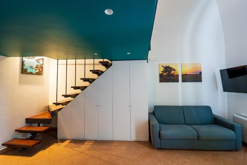 Un intérieur moderne avec un escalier, un canapé et des œuvres d’art accrochées aux murs.