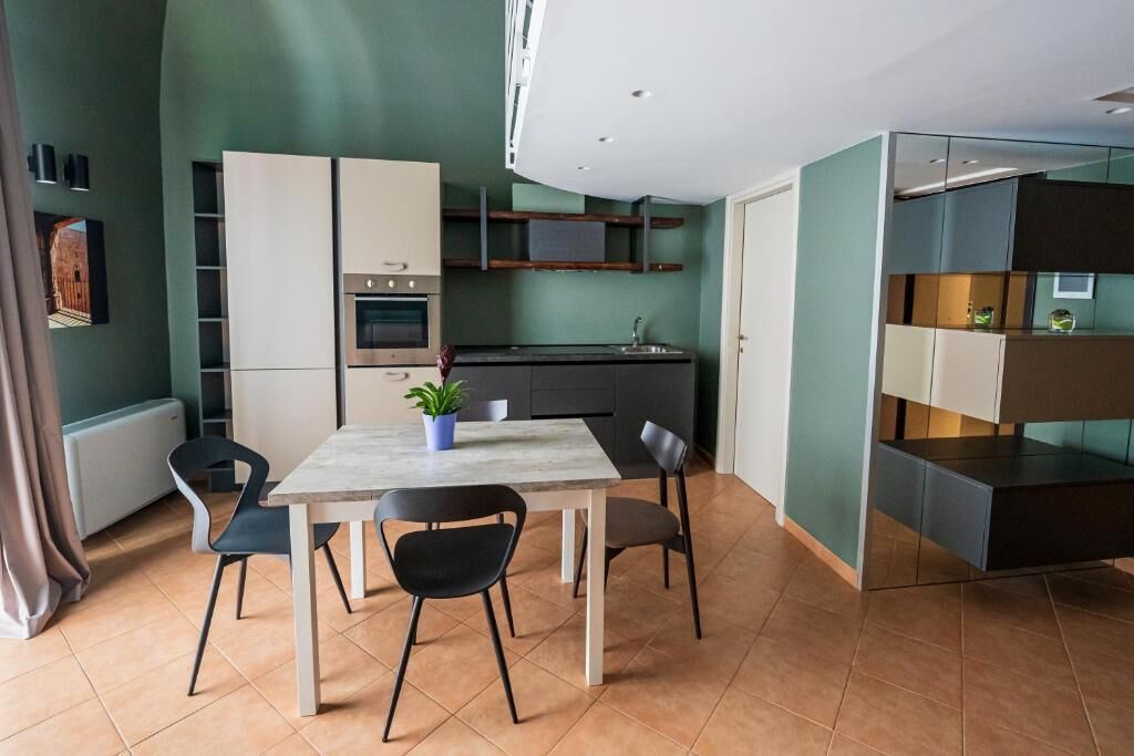 Une cuisine moderne dotée d’appareils électroménagers intégrés, un coin repas avec une table et des chaises, et une cloison en verre.