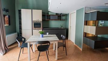 Une cuisine moderne dotée d’appareils électroménagers intégrés, un coin repas avec une table et des chaises, et une cloison en verre.