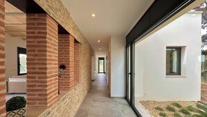 A corridor with a brick wall, a glass door, and a view of the outdoors. - The Private Accommodation Villa in Peralada (Peralada)