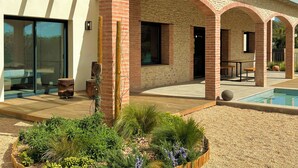 Une maison moderne dotée d’un patio, d’une piscine et d’un jardin.