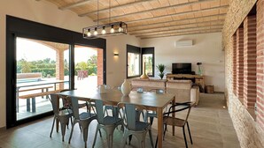 A modern interior with a dining area, a TV, and a brick wall. - The Private Accommodation Villa in Peralada (Peralada)