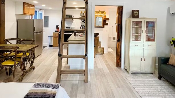 A loft-style room with a wooden staircase, a dining area, a kitchen, and a living room with a sofa. - Perfect Studio - Walking distance of Lava Hot Springs Pools (Lava Hot Springs)
