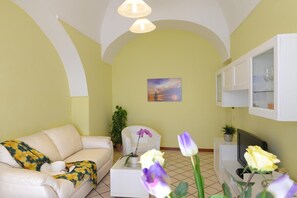 A living room with a sofa, a coffee table, a TV, and a painting on the wall. - Palazzo Rocco Villa Red Moon in Love – Sea View Terrace on the Amalfi Coast (Praiano)