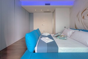 Una camera d'albergo moderna con un letto, una zona salotto e un'ampia decorazione a parete.