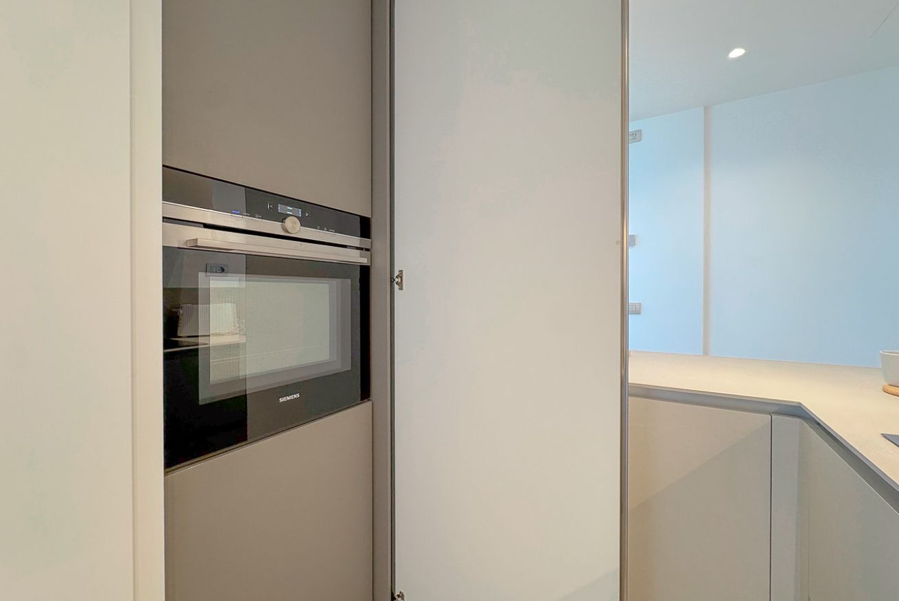 Eine moderne Küche mit integrierten Geräten, einer Glastrennwand und einem minimalistischen Design.