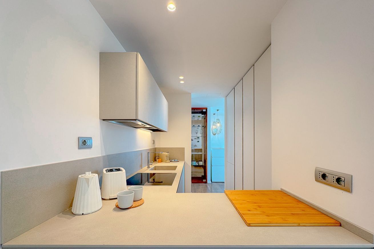 A modern kitchen with a wooden countertop, a built-in stove, and a ventilation hood.