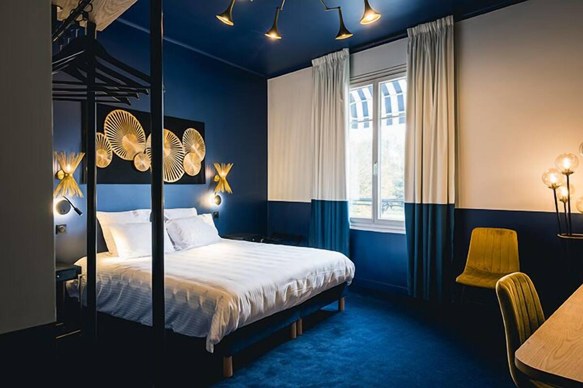 A bedroom with a bed, a desk, a chair, and a window with curtains.