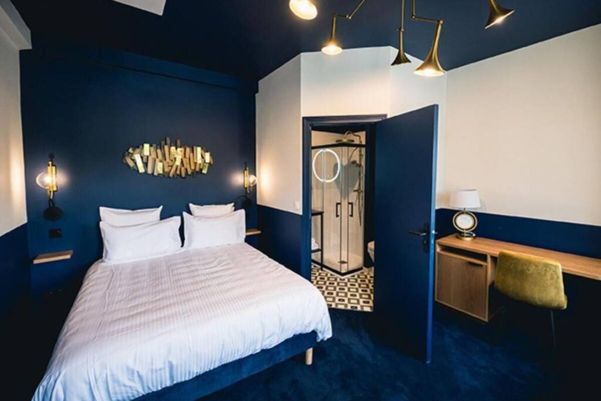 A bedroom with a bed, bedside tables, a desk, and a chair. There is a mirror and a wardrobe.