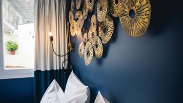 A room with a dark blue wall, a window with curtains, and a wall-mounted light fixture.