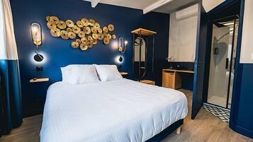 A bedroom with a bed, bedside tables, a mirror, and a wall art piece.