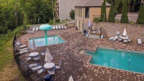 Ein Poolbereich auf dem Dach mit mehreren Pools, Liegestühlen und Sonnenschirmen.