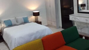 Un dormitorio con cama, mesita de noche con lámpara, armario y espejo.
