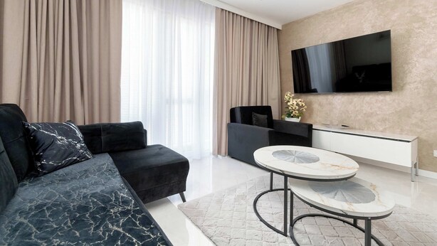 Un salon moderne avec un canapé, un téléviseur fixé au mur et une table basse ronde.