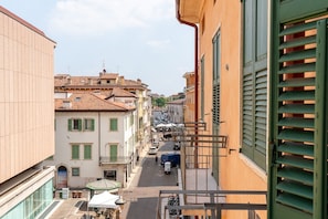 A narrow street with buildings on either side, a clear sky, and a few parked vehicles. - Centrally located elegant residence with balcony (Verona)