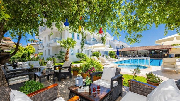 A poolside area with outdoor seating, a pool, and a view of white buildings.