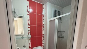 A bathroom with a toilet, bidet, and sink, with red and white tiles.