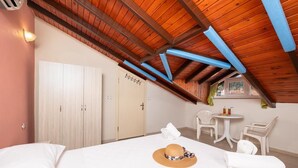 A bedroom with a wooden ceiling, a bed, a chair, a small table, and a window.