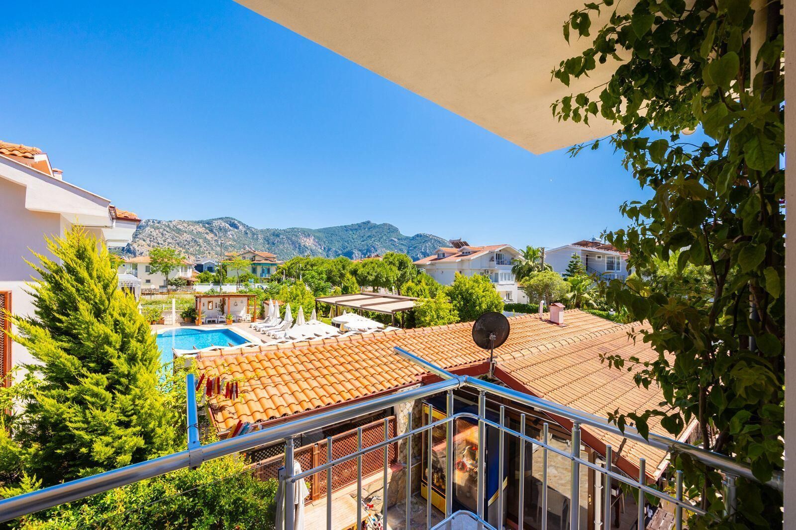 Zona residencial amb piscina, balcons i un paisatge de muntanyes al fons.