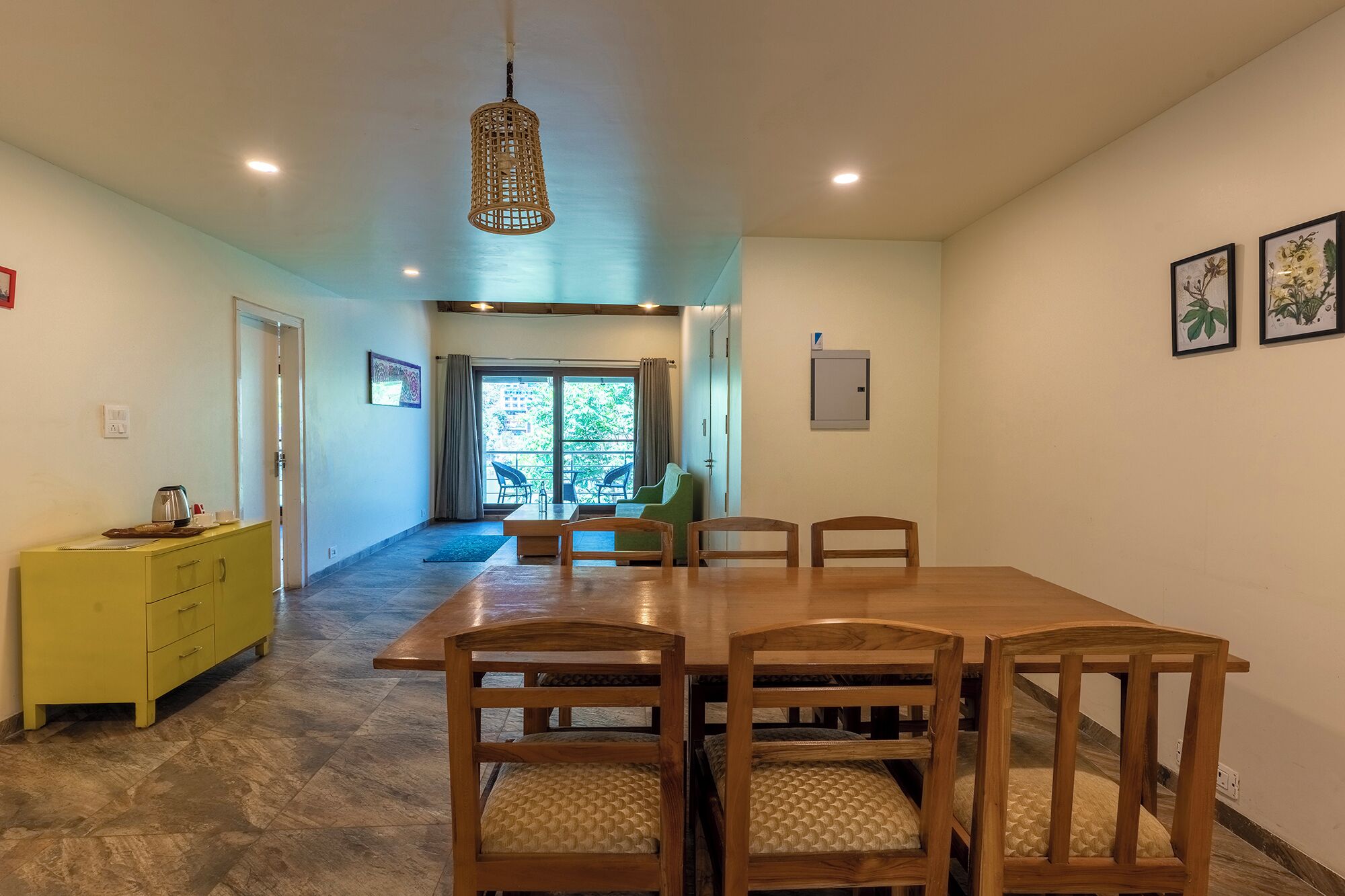 A dining area with a wooden table and chairs, a yellow cabinet, and a hanging light fixture.