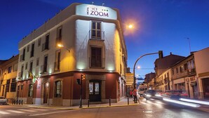 A hotel named 'HOTEL ZOOM' with a corner building, a visible entrance, and a street view with vehicles. - Hotel HC Zoom (Pozoblanco)