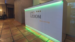 A reception desk with a sign reading 'HOTEL 700M' and 'Bienvenue@'. - Hotel HC Zoom (Pozoblanco)