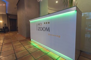 Un mostrador de recepción con un cartel que dice 'HOTEL 700M' y 'Bienvenue@'.