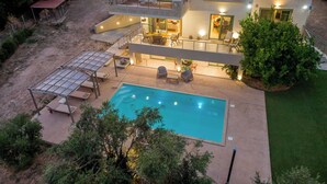 Uma casa de dois andares com piscina, área de estar externa e varanda coberta.