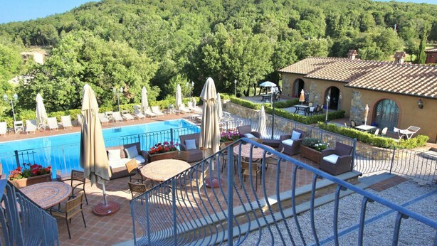 A rooftop pool area with lounge chairs, umbrellas, and a view of a forested hillside. - This studio apartment, approximately 23 square meters in size, sleeps two. It is tastefully furnished and air-conditioned. It features a kitchenette equipped with dishes, an oven, a refrigerator, satellite TV, a living room with a double bed, and a priva (Monteverdi Marittimo)