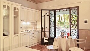 A kitchen with white cabinets, a dining table with chairs, and a view through a glass door. - This studio apartment, approximately 23 square meters in size, sleeps two. It is tastefully furnished and air-conditioned. It features a kitchenette equipped with dishes, an oven, a refrigerator, satellite TV, a living room with a double bed, and a priva (Monteverdi Marittimo)