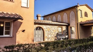 A building with stone and stucco exterior, arched windows, and a patio with outdoor furniture. - This studio apartment, approximately 23 square meters in size, sleeps two. It is tastefully furnished and air-conditioned. It features a kitchenette equipped with dishes, an oven, a refrigerator, satellite TV, a living room with a double bed, and a priva (Monteverdi Marittimo)
