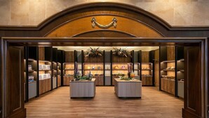 A hotel lobby with a central reception desk, wooden paneling, and decorative plants. - Oriental Hotel Okinawa Resort and Spa (Nago)